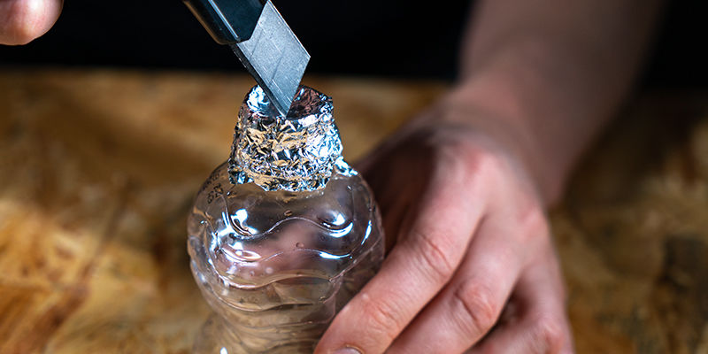 Irrota pullonkorkki ja kääri foliota ensimmäisen pullon suuaukon ympärille Ämpäri-gravity bong: Irrota pullonkorkki ja kääri foliota ensimmäisen pullon suuaukon ympärille