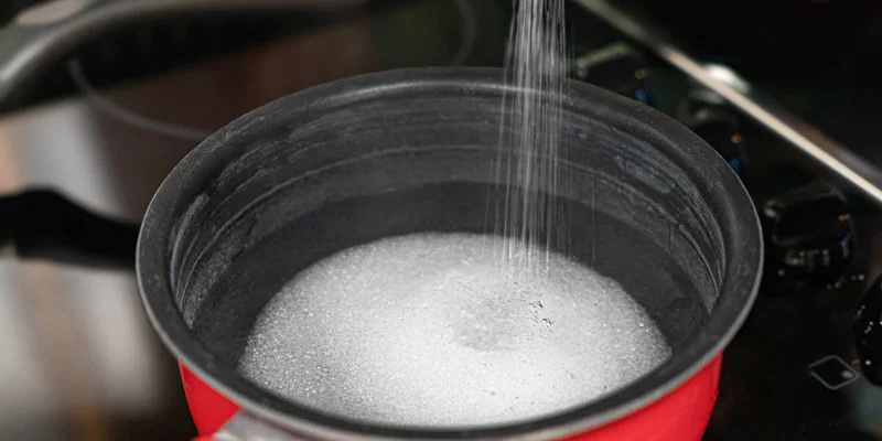 Sekoita vesi ja sokeri kattilassa ja kuumenna keskilämmöllä, kunnes sokeri liukenee täysin. Combine the water and sugar in a saucepan and heat at a medium temperature until the sugar dissolves completely.
